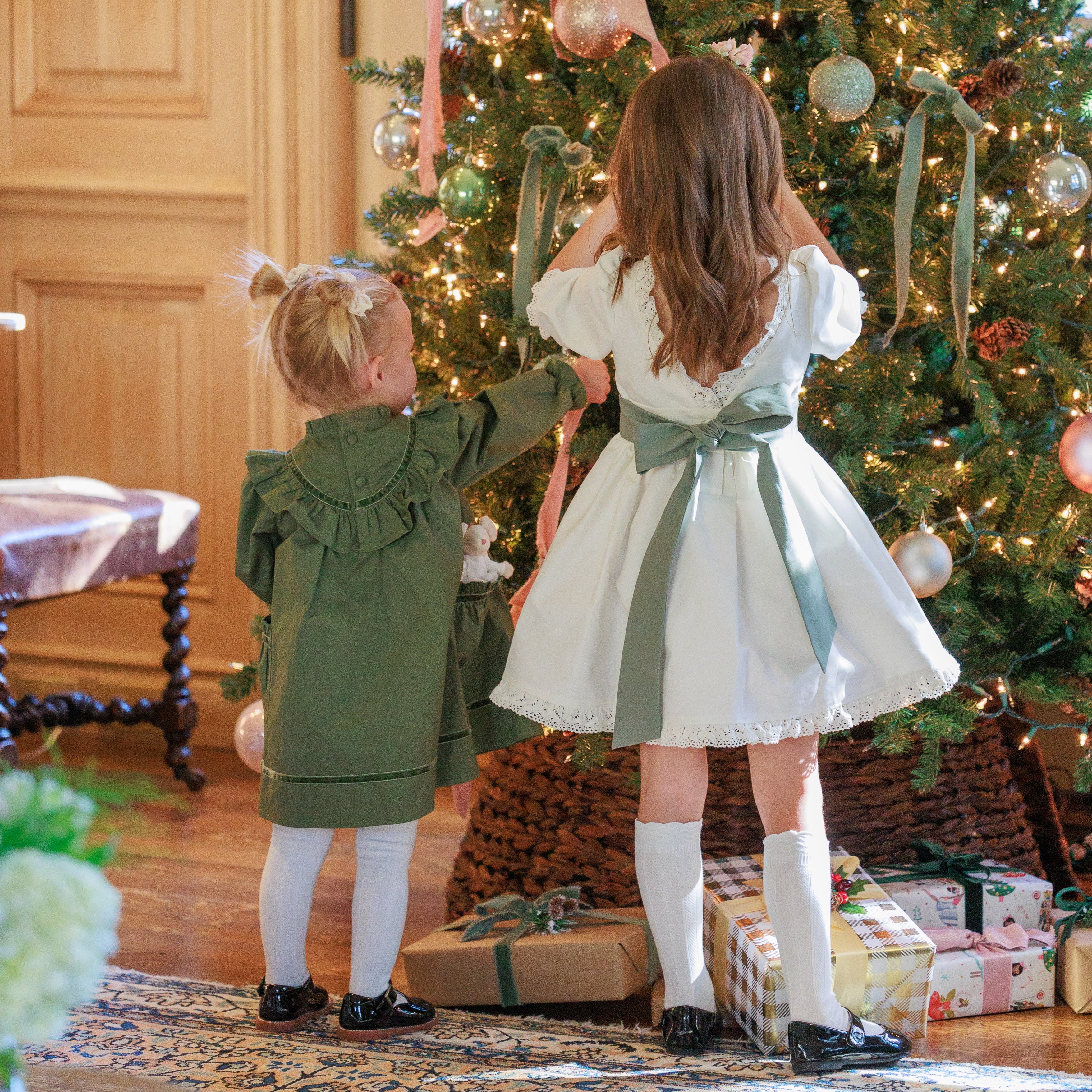 Two children decorating a Christmas tree with ornaments and ribbons.