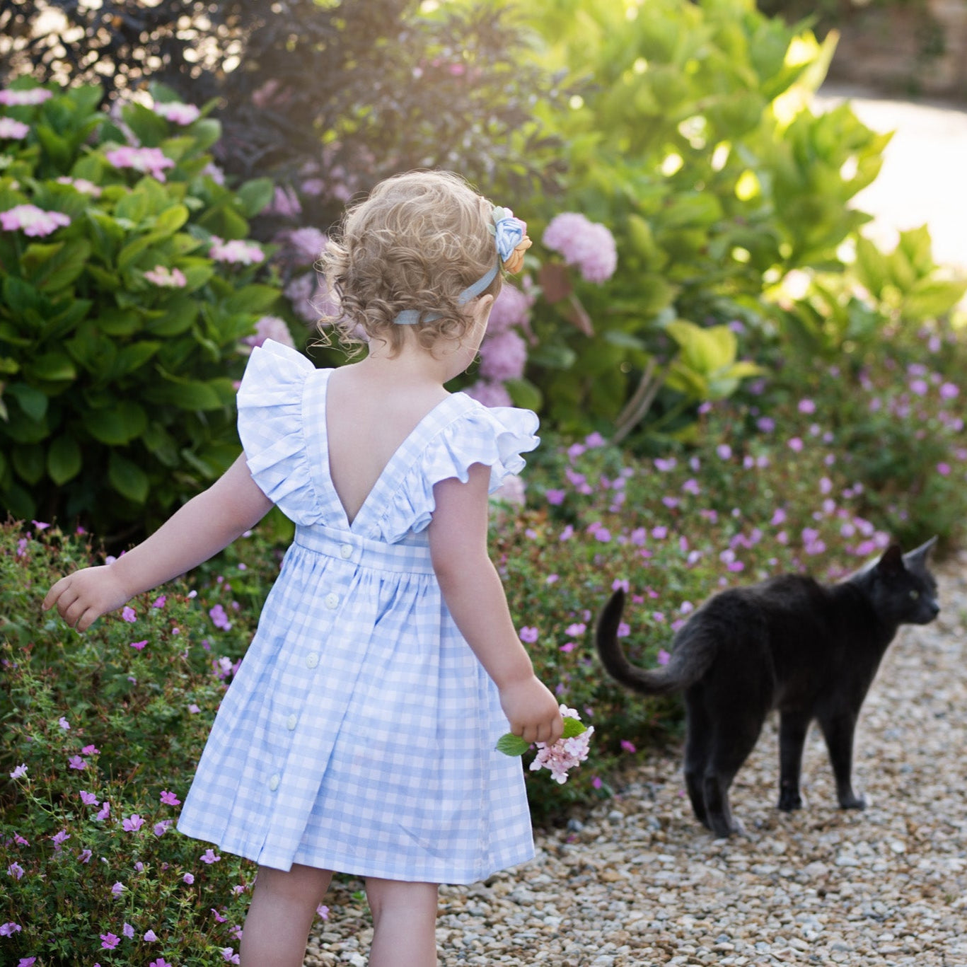 Young girl in a garden with a black cat